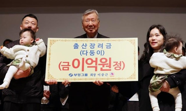 Chủ tịch Lee Jong-keun (giữa) chụp ảnh c&ugrave;ng gia đ&igrave;nh một nh&acirc;n vi&ecirc;n sau khi trao cho họ 200 triệu won tiền mặt trong buổi lễ đ&oacute;n năm mới tại trụ sở c&ocirc;ng ty ở Seoul. Ảnh: Yonhap